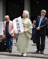 One of the plaintiffs holds a paper reading 