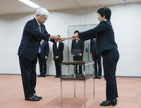 Japan Post President Tetsuya Senda (left) receives a document on the license revocation at the Kanto District Transport Bureau in Yokohama on Wednesday.
