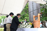 Attendees offer flowers at the cenotaph Monday during a memorial service for the victims of the Hanaoka mine incident, which occurred in Akita Prefecture on June 30, 1945, in the late stage of World War II.