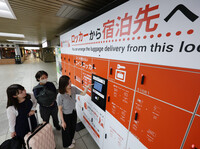 People use a locker-to-hotel luggage delivery service in Osaka on Monday