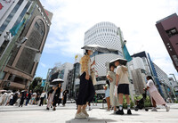 People walk with parasols in Tokyo's Ginza district after the rainy season ends in Kanto-Koshin and other areas on Friday.