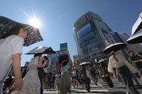 People walking at the iconic scramble crossing in Tokyo's Shibuya Ward amid intense heat on June 28